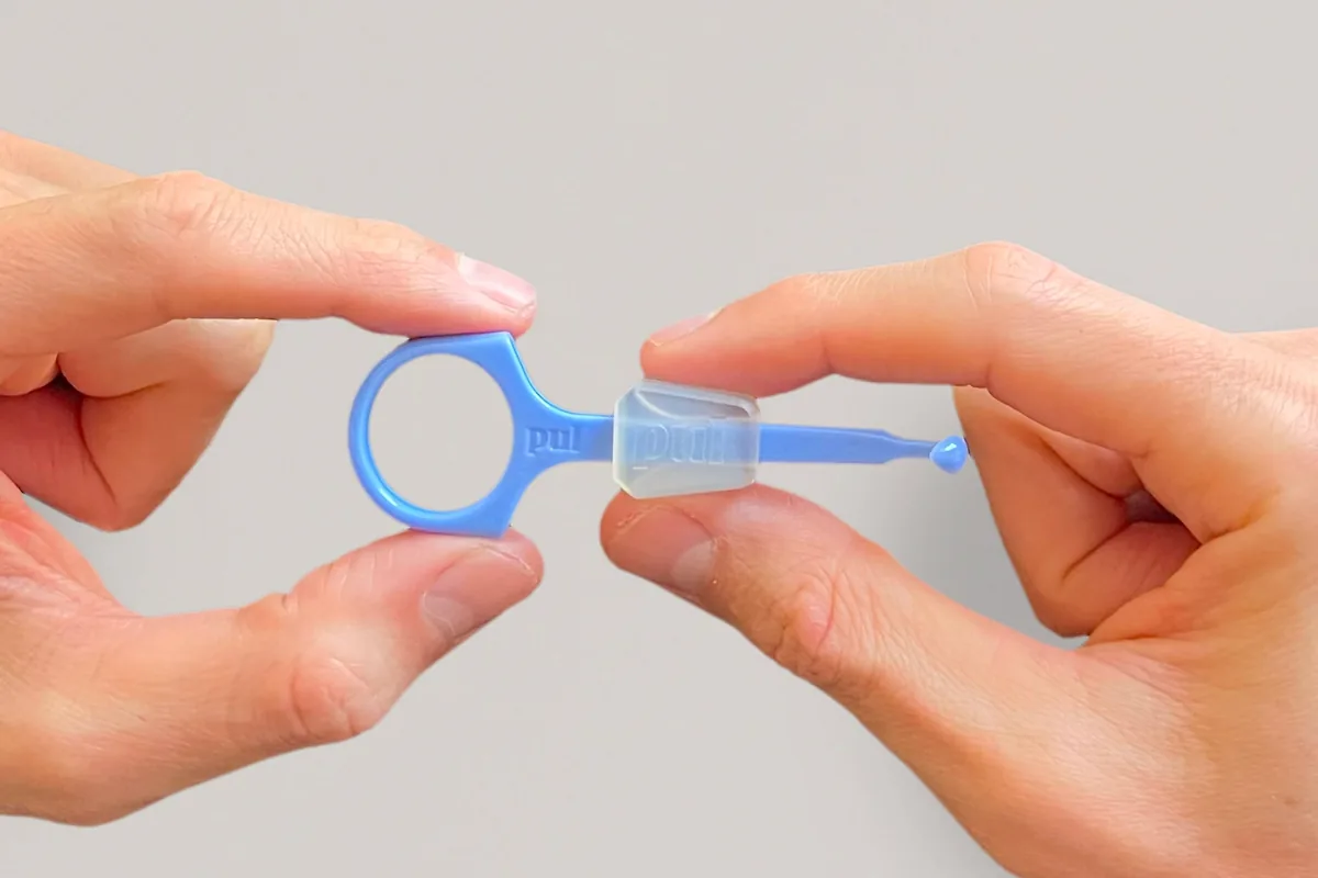 The PUL 2-in-1 aligner tool, light blue, held between two hands.