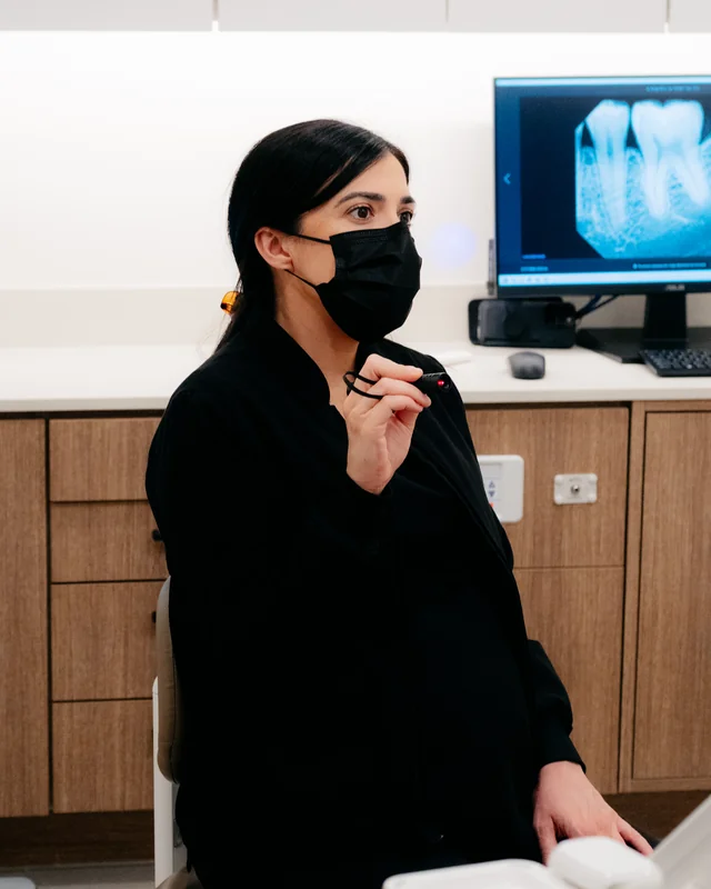 Dr. Sheila Heraypur in a treatment room at Springs Dental, with an X-ray on the screen behind her.