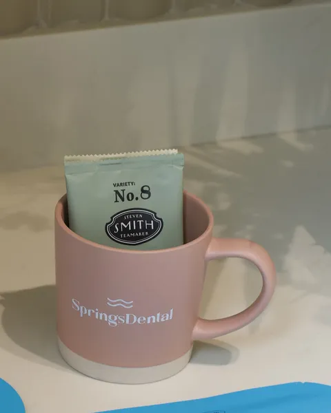 A Springs Dental mug with a tea sachet on a counter.